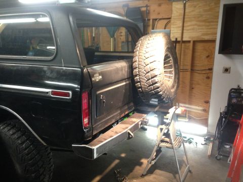 1979 Ford Bronco - The rear driver's side of a black Ford Bronco is shown, featuring a custom metal bumper and a spare tire mounted on the back. The vehicle i…