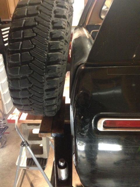 1979 Ford Bronco - A close-up side view shows a large off-road tire mounted on the rear of a black vehicle, possibly a Ford Bronco, supported by wooden blocks…
