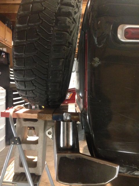 1979 Ford Bronco - A close-up side view shows the rear corner of a dark-colored vehicle, possibly a Ford Bronco, with a large spare tire mounted to the back.…