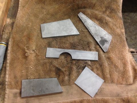 1979 Ford Bronco - Several metal pieces are laid out on a brown towel. One piece is a long rectangle with a semi-circular cutout in the middle. Another piece…