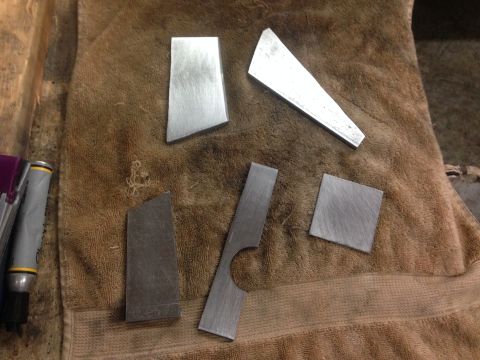 1979 Ford Bronco - Several pieces of metal are laid out on a brown towel. Some of the pieces are rectangular, one is square, and one is a trapezoid. There are…