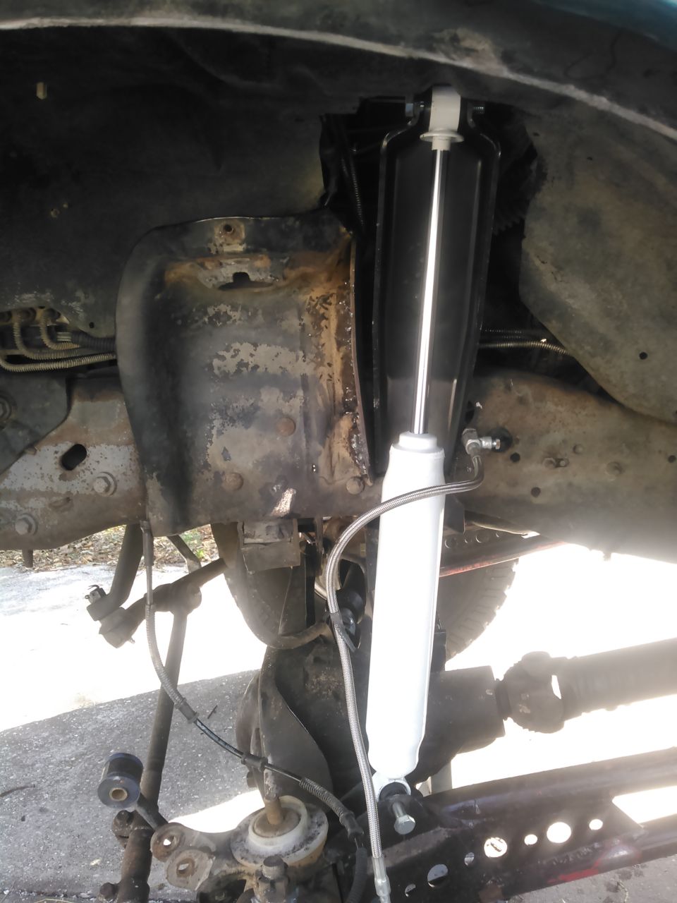 New shock absorber installed on a rusty 1996 Ford Bronco rear suspension.