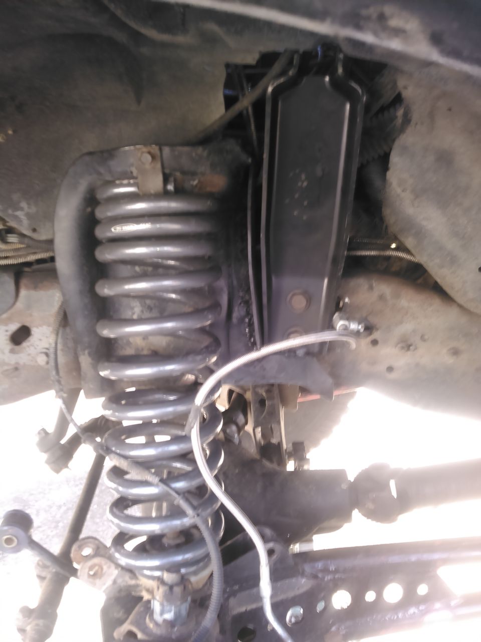 Vehicle front suspension with coil spring, shock, and drive shaft.