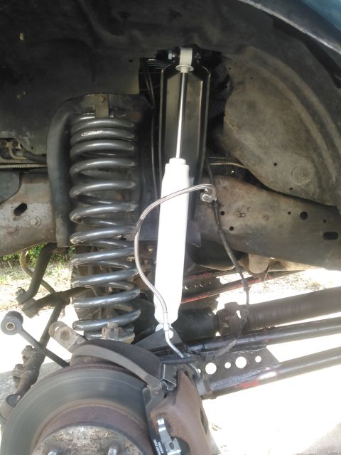 1996 Ford Bronco - The front suspension of a 1996 Ford Bronco is shown, featuring a large coil spring and a white shock absorber. The brake rotor and caliper…