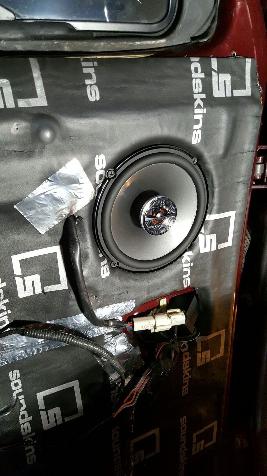 Car door interior with speaker installation, sound deadening material, and wiring.