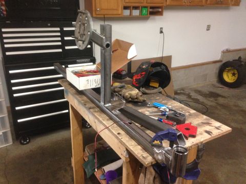 1979 Ford Bronco - A workbench in a garage setting with various metal fabrication tools and materials, including a welding helmet, gloves, metal stock, and a…