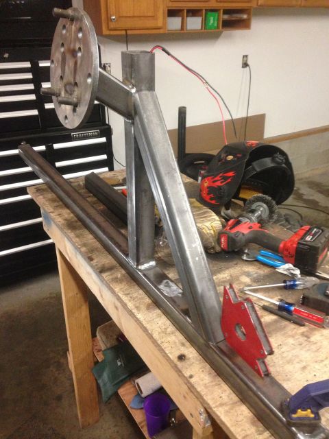 1979 Ford Bronco - A custom metal fabrication project, likely for a vehicle, is shown on a workbench. The project features a metal bracket with a wheel hub at…