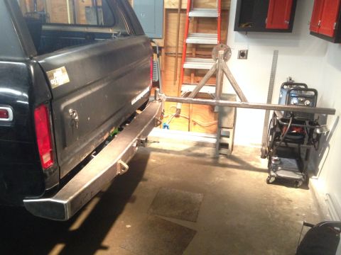 1979 Ford Bronco - The rear driver's side of a black Ford Bronco is shown with a custom-fabricated metal bumper installed. A welding cart and ladder are visib…