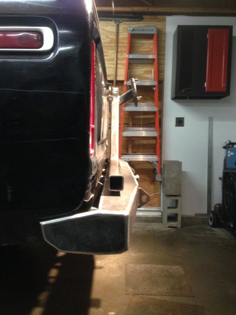 1979 Ford Bronco - The rear passenger side of a black vehicle, likely an SUV, is shown with a custom-fabricated metal bumper attached. A bright orange Louisvi…