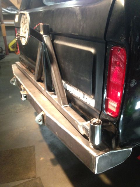 1979 Ford Bronco - The rear passenger side of a black Ford Bronco is shown with a custom-built steel rear bumper and spare tire carrier. The bumper features a…