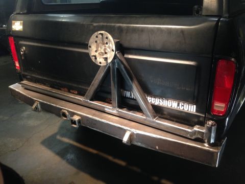 1979 Ford Bronco - The rear of a black 1979 Ford Bronco shows a custom-built steel bumper with a spare tire mount. A website address is visible on the tailgat…