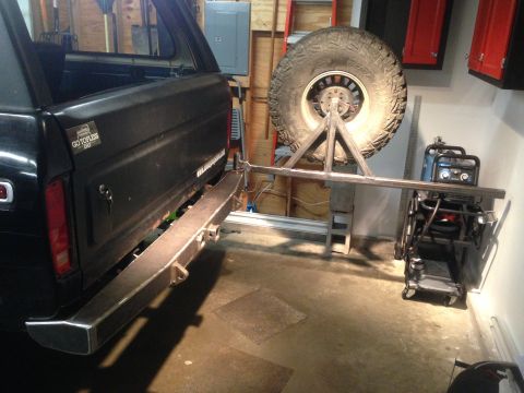 1979 Ford Bronco - The rear of a black Ford Bronco is shown with a custom-fabricated metal bumper. A spare tire is mounted on a stand behind the bumper, and a…