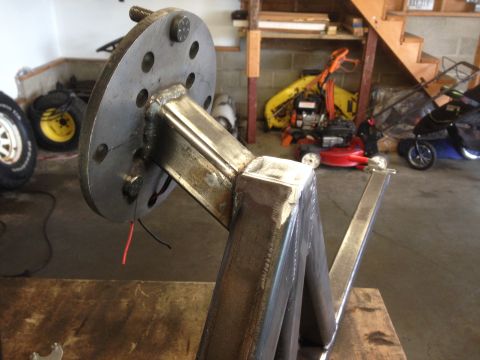 1979 Ford Bronco - A close-up view of a custom-fabricated metal bracket with a bolted flange, likely part of a vehicle modification. Red and black wires are v…