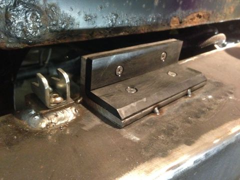 1979 Ford Bronco - A close-up view of a custom metal bracket with two L-shaped pieces bolted together, attached to a metal surface with visible welds. A U-sha…