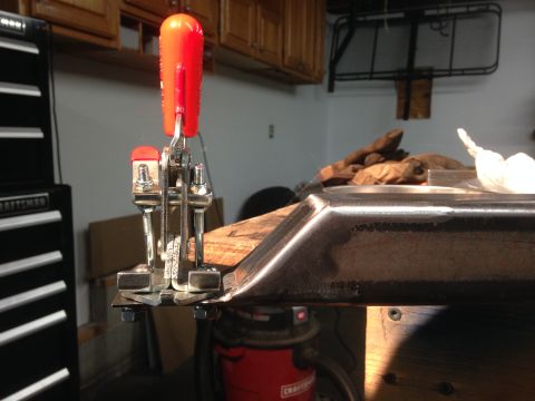 1979 Ford Bronco - A close-up view of a metal fabrication clamp holding a piece of metal with a beveled edge. The clamp has a red handle and is attached to a…