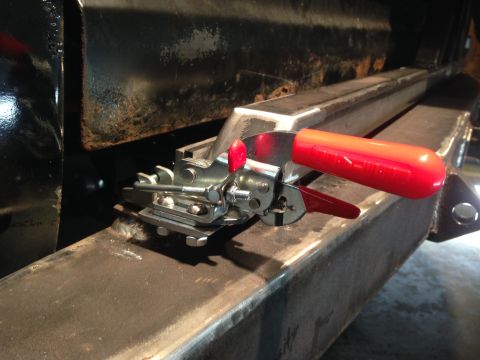 1979 Ford Bronco - A close-up view shows a metal latch mechanism with a red handle attached to a thick, dark metal beam. The beam appears to be part of a vehi…