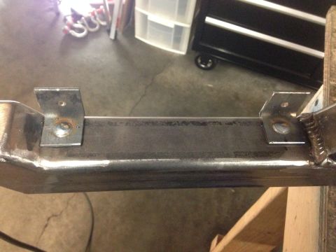 1979 Ford Bronco - Close-up view of two metal brackets welded onto a rectangular steel tube, likely part of a custom vehicle frame or modification. The bracke…