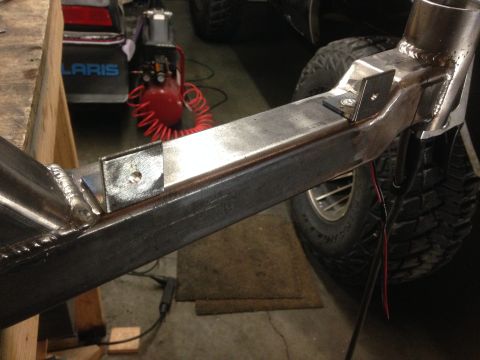 1979 Ford Bronco - A close-up view of a custom metal frame, likely part of a vehicle modification, showing welded joints and mounting brackets. A tire and par…