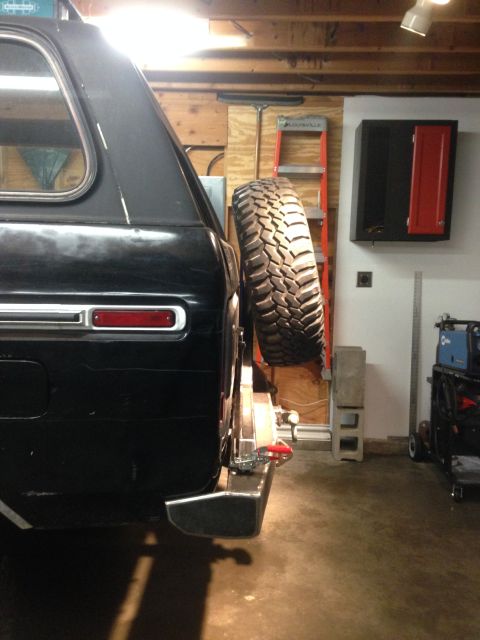 1979 Ford Bronco - The rear driver's side of a black SUV with a spare tire mounted on the back. The vehicle is parked in a garage with tools and equipment vis…