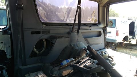 1994 Ford Bronco - Interior view of a disassembled vehicle, likely a Ford Bronco, showing the rear passenger side panel, seat, and a discarded dashboard piece…