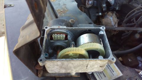1994 Ford Bronco - The image shows an open gear housing with a motor and two plastic gears inside. A wiring harness connector is visible on the left side of t…