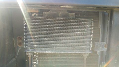 1994 Ford Bronco - A close-up view of the front of a 1994 Ford Bronco, showing the transmission cooler mounted in front of the radiator. The cooler has a finn…