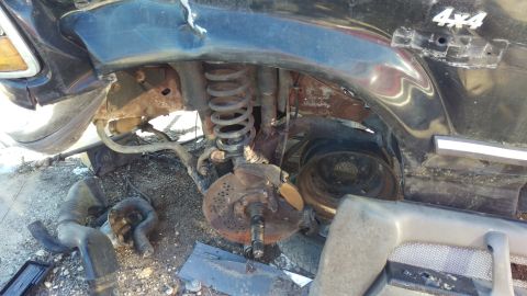 1994 Ford Bronco - This is a close-up view of the front passenger-side suspension and wheel well area of a black 4x4 SUV, likely a 1994 Ford Bronco, showing s…