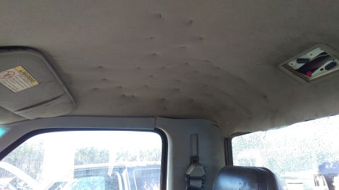 1994 Ford Bronco - The interior of a vehicle shows a sagging headliner with numerous indentations and a detached section near the rear window, which is cracke…