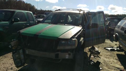 1994 Ford Bronco - A damaged green SUV with its hood open and driver's side door ajar is parked in a junkyard. The front end of the SUV is heavily damaged, wi…