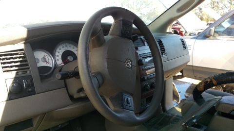 1994 Ford Bronco - The interior of a vehicle shows the steering wheel, dashboard, and gauges. The vehicle appears to be in a junkyard setting with other vehic…