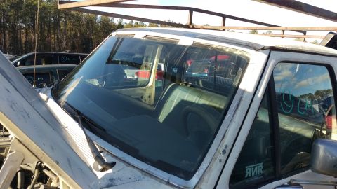 1994 Ford Bronco - The interior of a white pickup truck is visible, including the windshield, dashboard, seats, and a portion of the driver's side door. The t…