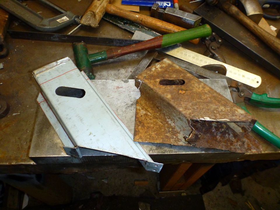 Workbench with tools and metal parts, including two angled metal brackets.