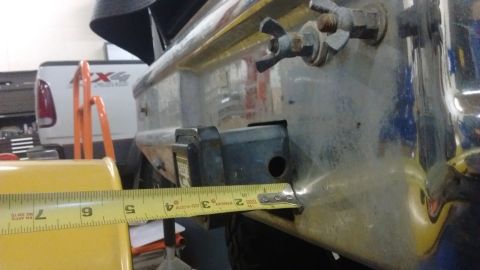 1985 Ford Bronco - Measuring trailer hitch receiver dimensions. A white Ford F-series truck is visible in the background.