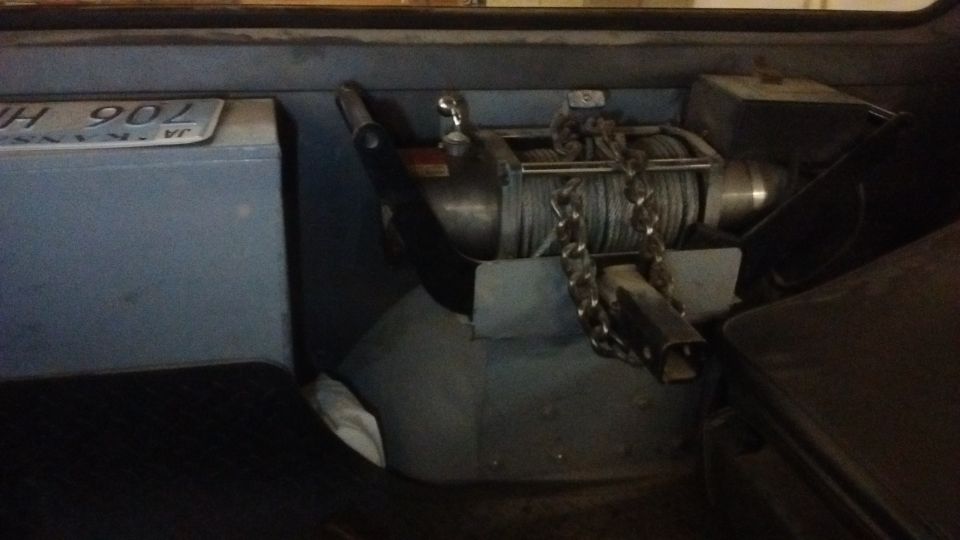 Winch with chain mounted behind a blue storage box with license plate 'JH 902'
