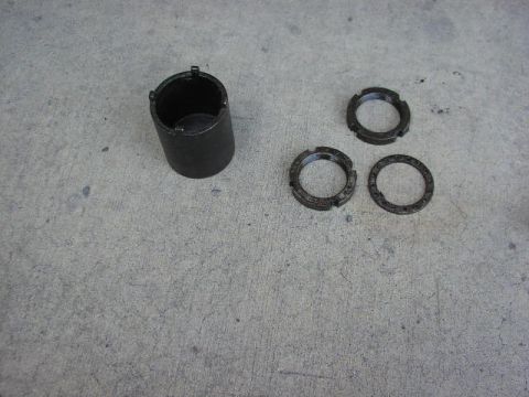 1986 Ford Bronco - A black wheel bearing lock nut tool is shown with three lock nuts on a concrete surface.