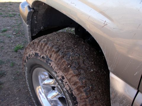 1990 Ford Bronco - Close-up of a muddy tire and fender on a truck after off-roading.