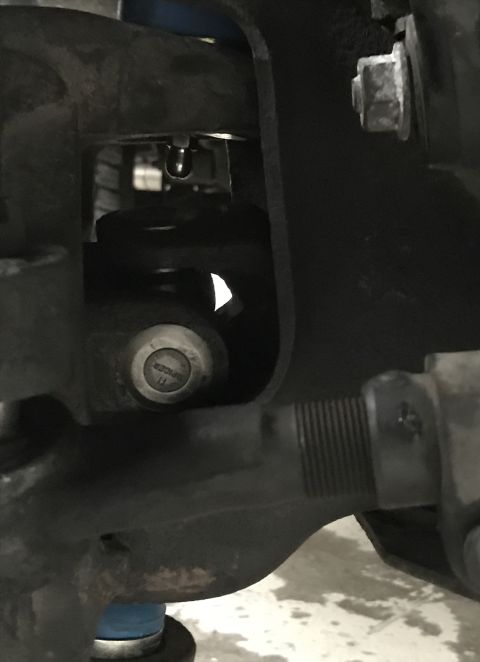 1995 Ford Bronco - A close-up view of a vehicle's suspension system, focusing on a specific component and a bolt with a warning.
