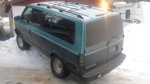 1995 GMC Safari - The van has a two-tone paint scheme and roof racks, parked in a snowy area next to a building.