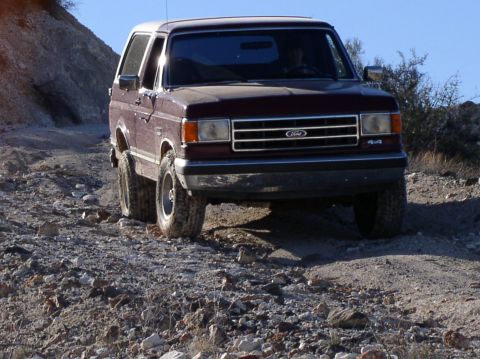 1990 Ford Bronco - This 1990 Ford Bronco navigates a , off-road path under a clear blue sky.
