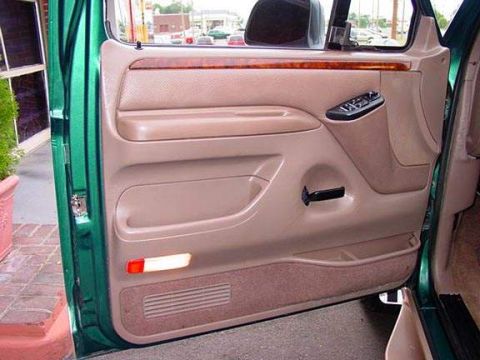 1996 Ford Bronco - Interior view of a 1996 Ford Bronco's driver's side door panel, tan upholstery and wood accents.