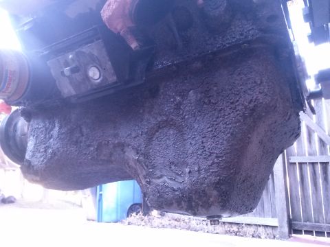 1996 Ford Bronco - The underside of an engine shows a heavily soiled oil pan, indicating a need for maintenance.