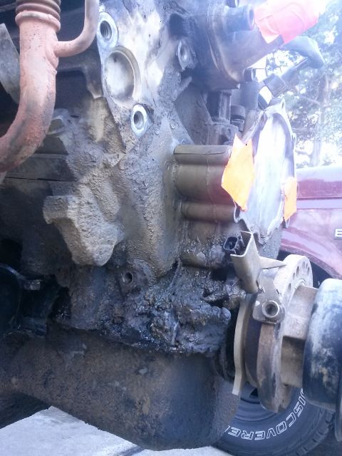 1996 Ford Bronco - Close-up of a greasy engine block with visible tape and a metal flange attached.