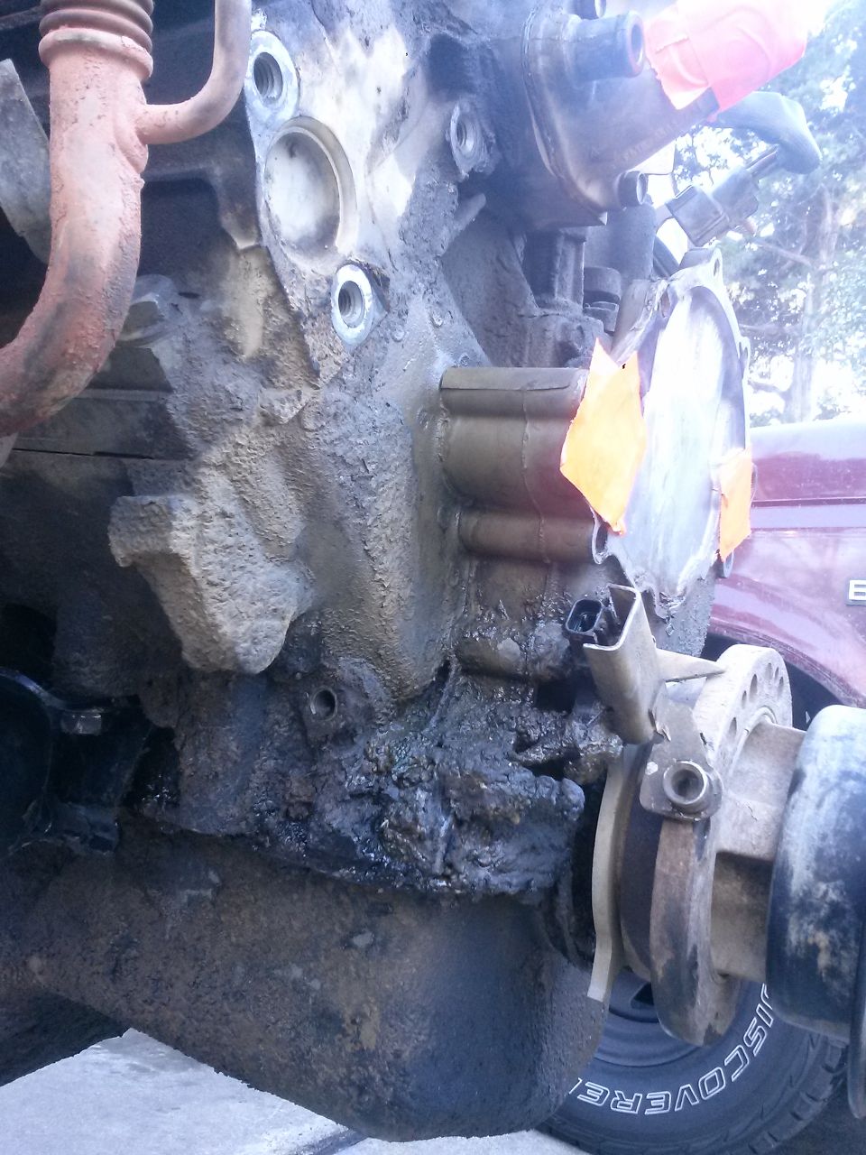 Dirty engine block with orange tape and a metal flange
