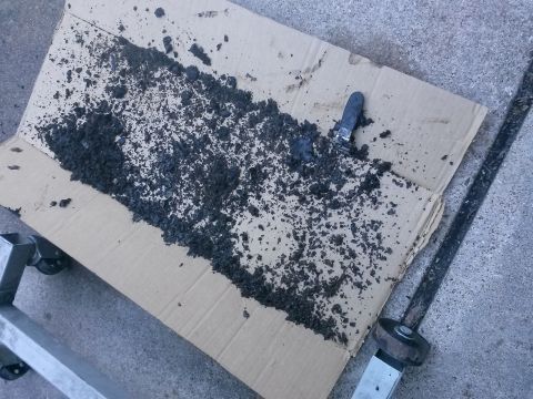1996 Ford Bronco - Debris from an engine re-seal project is spread out on cardboard for examination.