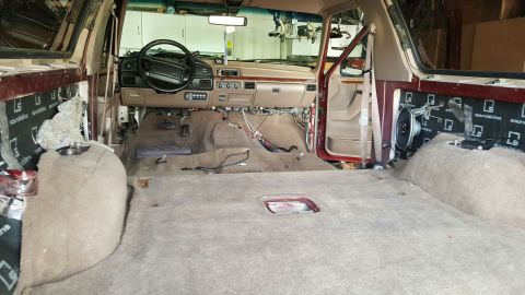 1996 Ford Bronco - Interior of a 1996 Ford Bronco during sound deadening installation, showing removed carpet and exposed panels.
