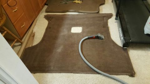 1996 Ford Bronco - Sound deadening material is laid out on the floor, with a vacuum hose attached, next to a treadmill.