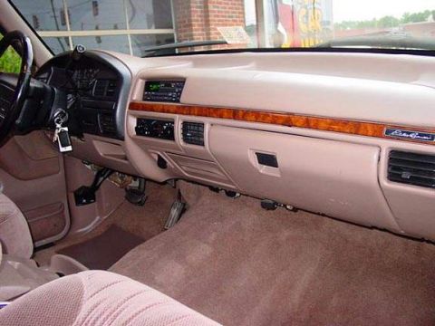 1996 Ford Bronco - The interior of a 1996 Ford Bronco shows its dashboard with wood grain trim and an Eddie Bauer badge.