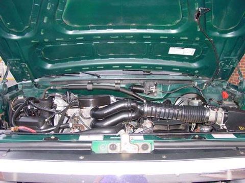 1996 Ford Bronco - The engine bay of a green vehicle is shown with the hood open, revealing the engine and various components.