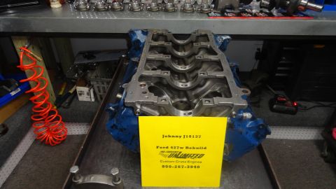 1982 Ford Bronco - A Ford 427w engine block is displayed on a workbench with a yellow sign detailing the rebuild and a Supermotors logo.