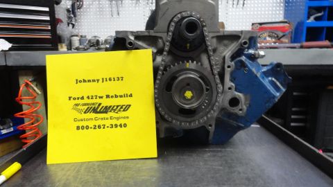 1982 Ford Bronco - Engine block with timing chain and gears, accompanied by a yellow sign detailing a rebuild.